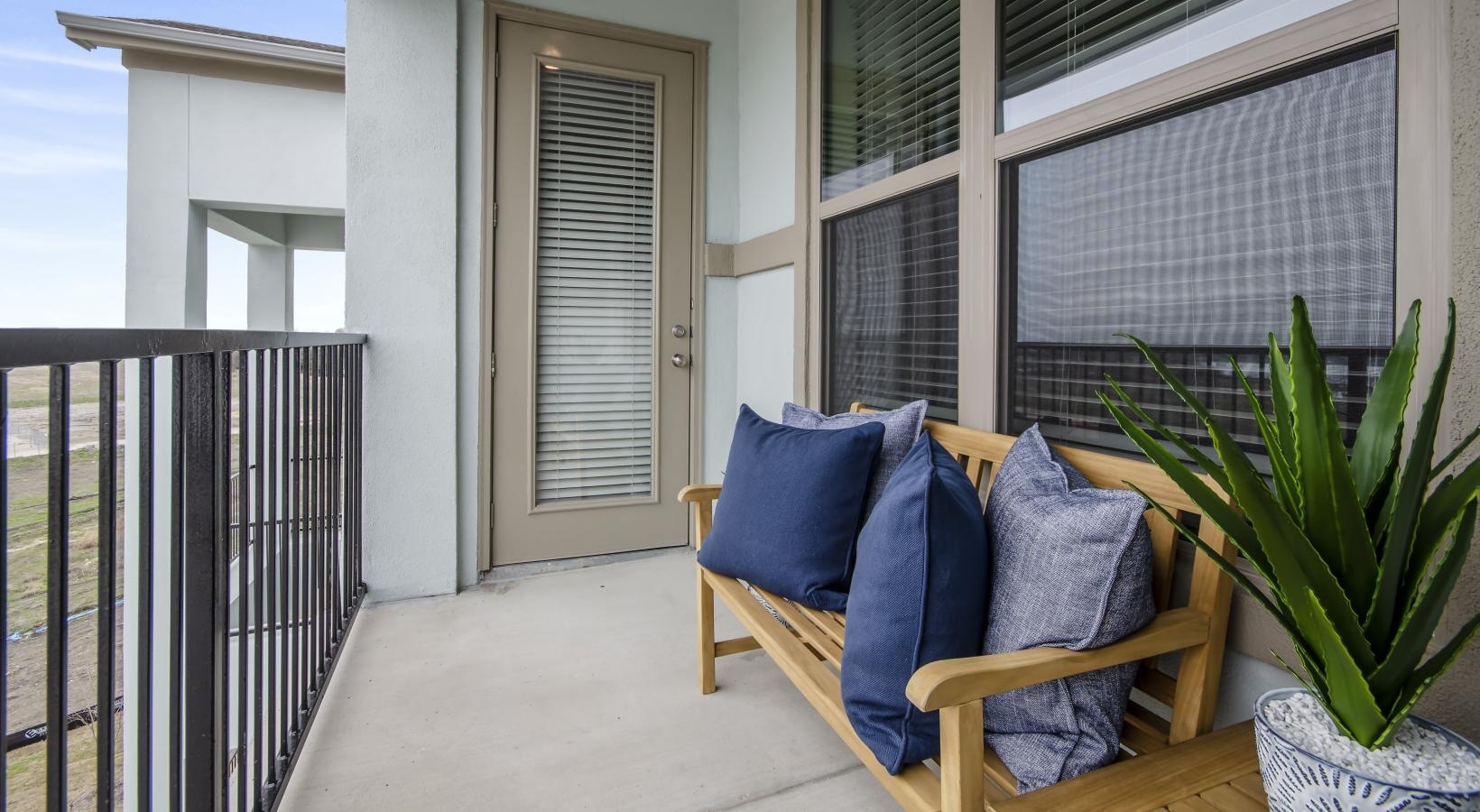 All the comforts of luxury living a patio with a blue couch and a plant on it
