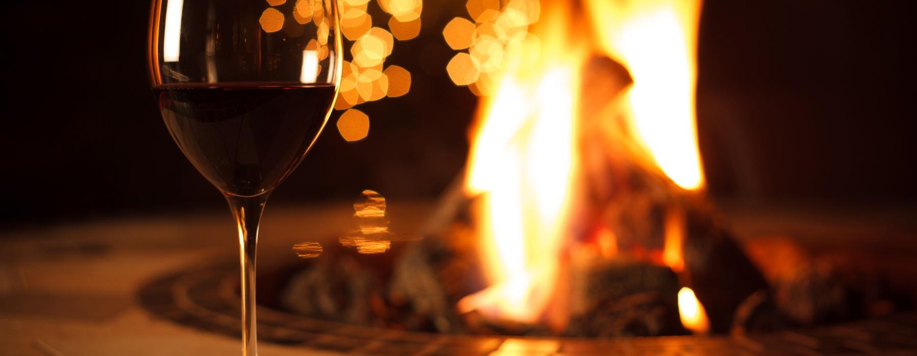 a glass of wine next to a fire